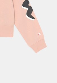 Manica di felpa rosa con un design ondulato a contrasto bianco e nero, polsino a coste e piccolo logo sulla cucitura inferiore.