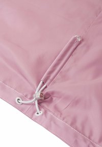 Tessuto rosa con un cordoncino bianco e un fermaglio in plastica utilizzato per regolare la tensione su un indumento o il bordo di una borsa.