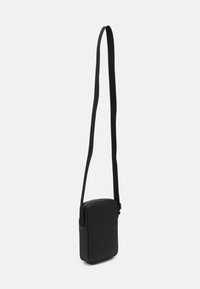 Borsa a tracolla nera con forma rettangolare, texture liscia, chiusura con zip e tracolla regolabile. Design minimalista senza pattern.