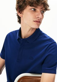 Marineblauw polo-shirt van een gestructureerde gebreide stof, met een kraag en korte mouwen; heeft een subtiele geborduurde logo op de borst.