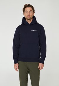 Sudadera de algodón azul marino con un gran bolsillo delantero, capucha con cordón y un pequeño logo blanco en el pecho. Cuenta con puños y dobladillo acanalados.