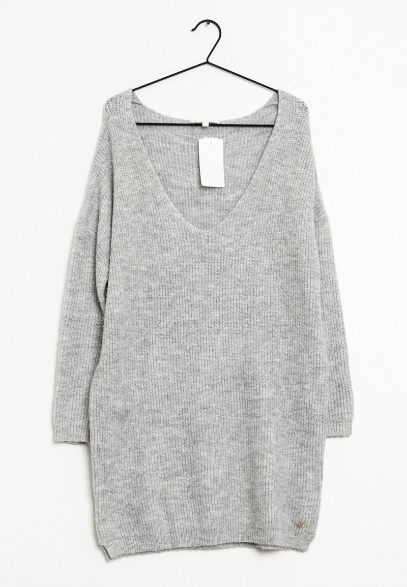 Maglione grigio chiaro, a maniche lunghe, lavorato a maglia, con scollatura a V, appeso a un appendiabiti nero su sfondo bianco.