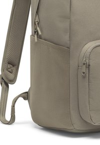 Rucsac bej, cu țesătură texturată, un buzunar lateral cu fermoar și bretele captusite pentru confort. Material durabil cu detalii discrete.