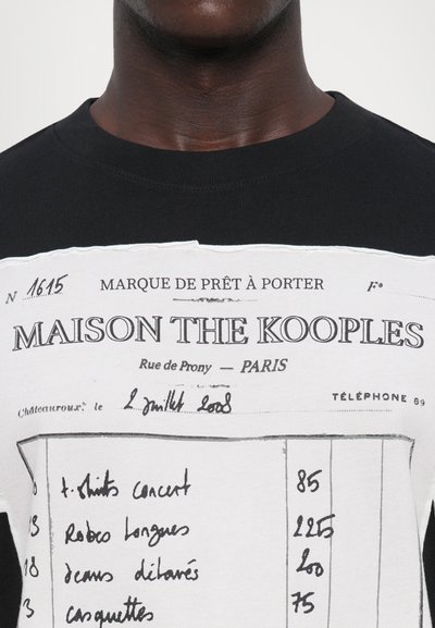 T-shirt en coton noir avec un design imprimé blanc ressemblant à une feuille de commande de vêtements, avec du texte et des chiffres manuscrits en encre contrastante.