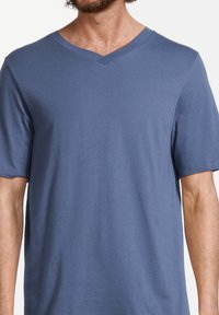 T-shirt bleu à col en V en tissu doux. Manches courtes et coupe décontractée. Texture lisse sans motifs ou logos visibles.