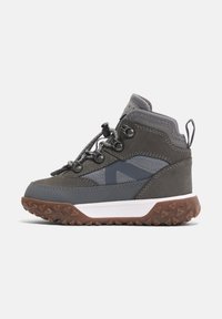 Šedá turistická bota s semišovým a syntetickým svrškem, gumovou podrážkou, výrazným zavazovacím systémem a polstrovaným límcem.