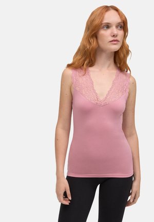 Camiseta de tirantes rosa con un profundo escote en V y un intrincado borde de encaje en los hombros. Tejido suave y elástico con un diseño ajustado. Pantalones negros visibles.