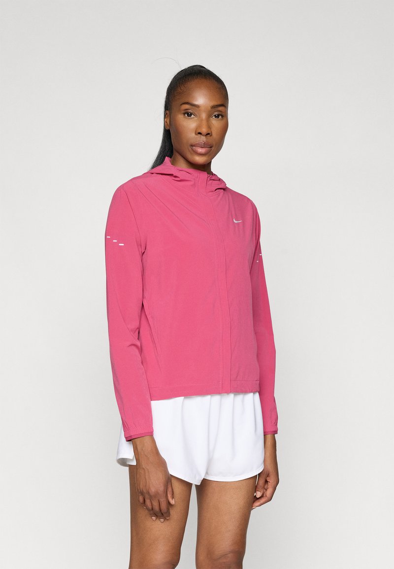 Veste légère rose avec capuche et manches longues, dotée d'accents réfléchissants sur les épaules et d'une fermeture éclair devant.