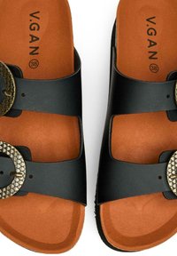 Black sandals with two wide straps, featuring a circular metal buckle with a textured pattern. The footbed is brown with a smooth finish.