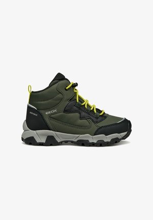 Chaussure de randonnée verte et noire avec lacets jaunes, semelle grise rugueuse, maintien de cheville rembourré et marquage sur les côtés et le talon.