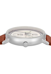 Reloj de metal plateado con una esfera redonda, dial crema, dos subesferas, manecillas verde y negra, y una correa de cuero marrón.