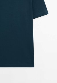 Donker teal katoenen t-shirt met korte mouwen, een ronde halslijn en een gladde textuur; heeft een rechte zoom en minimale details.