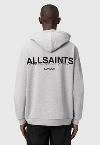 Szürke kapucnis pulóver fekete "ALLSAINTS" és "LONDON" felirattal a hátsó részén; laza szabása és puha textúrája van.