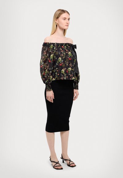 Blusa negra de flores con escote sin hombros y mangas abullonadas, con un detalle de lazo. Combinada con una falda midi negra ajustada y sandalias de tiras.