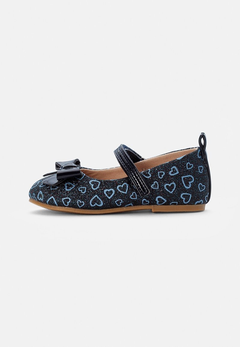 Chaussure plate noire scintillante pour enfant avec des motifs de cœurs bleus, un nœud sur le bout, une bride sur le coup de pied et une semelle en caoutchouc beige.