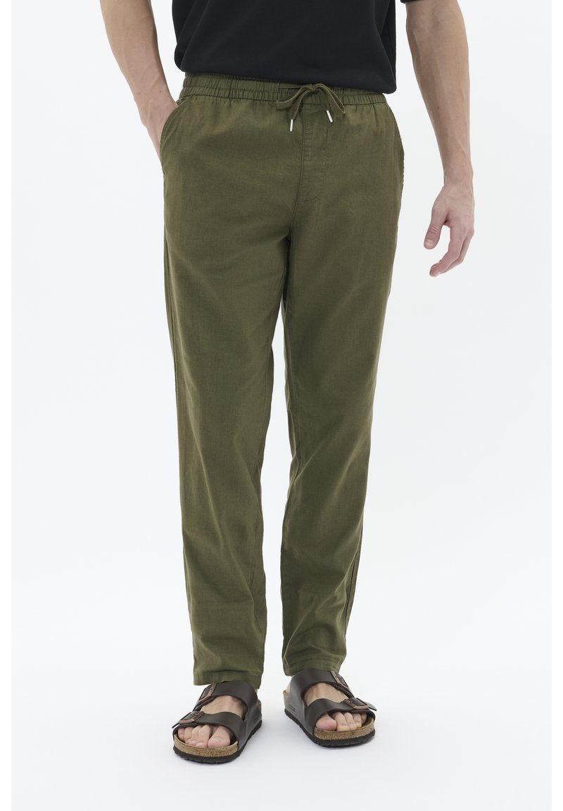 Olive green, lightweight pants with an elastic waistband and drawstring. Smooth texture, tapered design, two side pockets, paired with sandals.