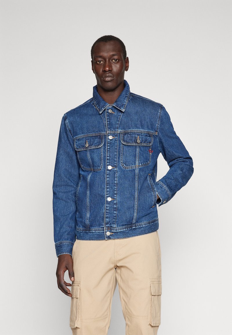 Denim jack in medium blauw met een klassiek ontwerp, voorzien van knoopsluiting, twee borstzakken en zijzakken; gladde textuur.