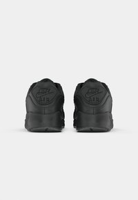 Schwarze Nike Air Sneaker mit strukturiertem Obermaterial, gepolsterter Schuhkragen und Gummilaufsohle. Logo und Markenaufdruck am Absatz geprägt.