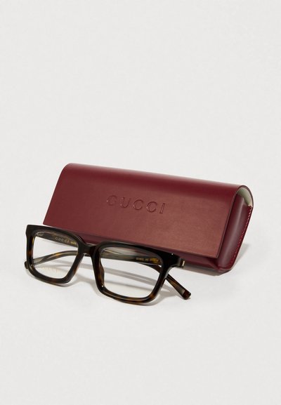 Gafas rectangulares Gucci con patrón de carey, acompañadas de un estuche de cuero burdeos con logo grabado.