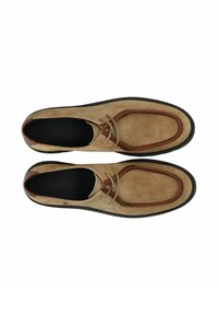 Nahkanilkkurit vaaleanruskeina ja tummanruskeina, pyöristetyt kärjet, nyöritys ja kuvioitu pohja. Yksityiskohtina kontrastivärinen reunus ja sileä sisäpinta.