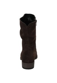 Bottine en daim marron avec un design légèrement affaissé, un talon en bois bas et un bord supérieur en zigzag. Comprend une fermeture éclair sur le côté.