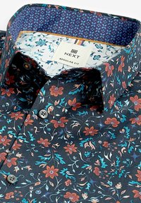 Camicia nera a fiori con motivi di fiori e fogliame multicolori. Rivestimento del colletto in contrasto di colore blu navy con design geometrico. Vestibilità regular.