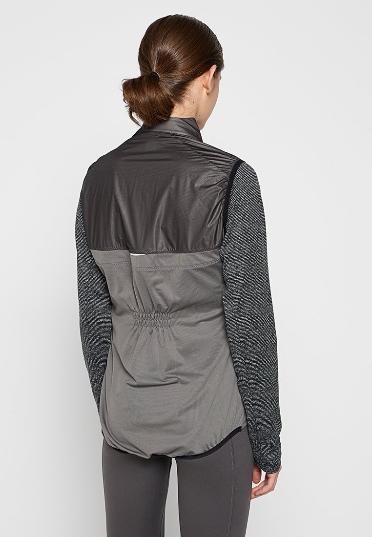 Graue Sportjacke mit leichtem Kragen, elastischem Bund und langen Ärmeln aus einem strukturierten dunkelgrauen Stoff.