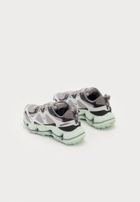 Chaussures de sport Merrell avec une tige en maille grise et blanche ornée d'accents noirs, une semelle épaisse en vert menthe et une languette au talon pour un enfilage facile.