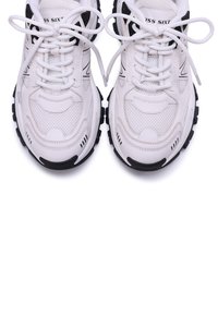 Scarpe da ginnastica bianche con accenti neri, materiali sintetici e in rete, suola in gomma nera spessa e punta tonda. I lacci si infilano attraverso gli occhielli.