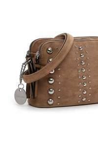 Braune Wildledertasche mit silbernen Nieten, Reißverschluss, Kettenriemen und einem Anhängeretikett. Sie besitzt eine glatte Oberfläche und eine kompakte rechteckige Form.