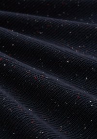 Marineblaues Textilgewebe mit gerippter Struktur, das mit roten und weißen Sprenkeln durchzogen ist. Flexibles und leicht dehnbares Material.