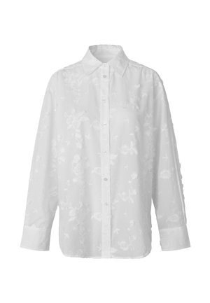Camisa blanca de manga larga con botones, con patrón bordado floral y cuello puntiagudo.