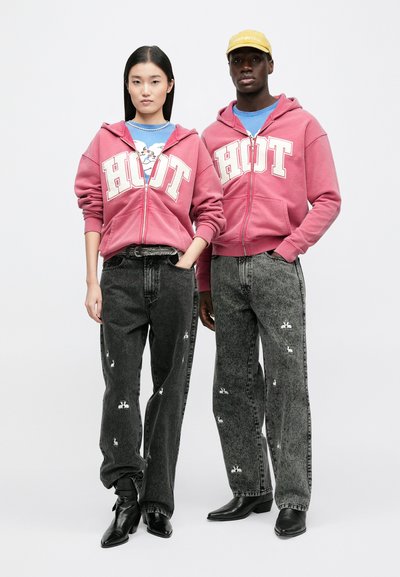 Pink zip-up hoodie with "HOT" print, paired with black jeans featuring white rabbit embroidery. Black pointed boots complete the look.
