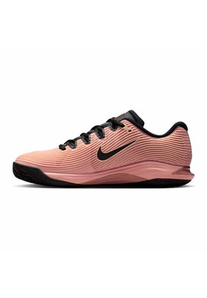 Scarpa da ginnastica rosa a basso profilo con lacci neri, suola nera e logo Nike swoosh nero sul lato, vista laterale.