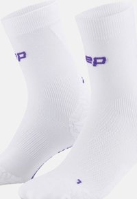 Weiße Sportsocken mit gerippter Textur, knöchellang, mit einem lila Logo und verstärktem Fersen- und Zehenbereich für Langlebigkeit.