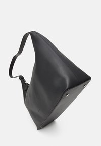 Svart läderhandväska med lös design, triangulär form och slät textur. Har silverdetaljer vid de nedre hörnen.