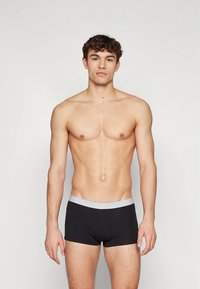 Cuecas boxer pretas com cós elástico cinzento, feitas de tecido macio, apresentando um design ajustado e estilo minimalista.