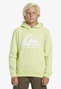 Felpa verde lime realizzata in tessuto morbido, con un grande logo Quiksilver bianco e una tasca a marsupio frontale. Vestibilità standard con cappuccio regolabile.