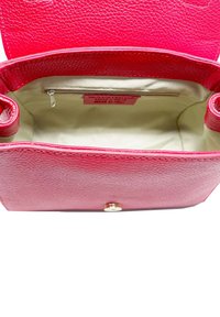 Punainen nahkainen käsilaukku, jossa on teksturoitu pinta, beige sisustus, vetoketjullinen tasku ja kultainen napin sulkemismekanismi.