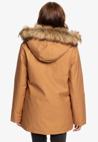 Parka marrón con capucha forrada de piel sintética, que presenta un corte recto y un cordón ajustable en la cintura. Vista trasera.