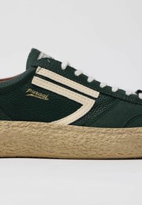 Sneaker verde con texture e dettagli crema, dotato di una robusta suola beige e lacci bianchi. Il logo dorato sul lato aggiunge un tocco di raffinatezza.