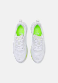 Baskets blanches de sport avec une tige en mesh respirant, bout arrondi et semelle extérieure vert néon. Comprend des lacets et un logo sur la semelle intérieure.