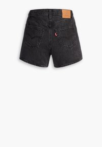 Short en denim noir avec poches arrière, passants de ceinture et un patch en cuir de la marque sur la taille, vu de dos sur un fond blanc.