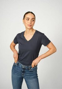 Námořnická modrá v-neck tričko vyrobené z měkké látky, spárované se světle modrými džíny. Tričko má krátké rukávy a uvolněný střih.