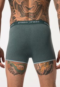 Boxers oscuros verdes con una cinturilla contrastante en gris claro que presenta la marca "JP1880". Tela suave con una textura lisa.