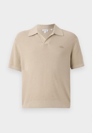 Polo shirt beige con un design a maglia testurizzato, maniche corte e colletto a V. Presenta un piccolo logo ricamato sul petto.