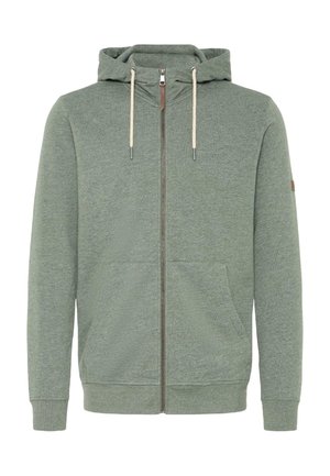 Grønn hettejakke med glidelås laget av myk materiale, med hette, snordekorer, frontlommer og ribbede mansjetter.