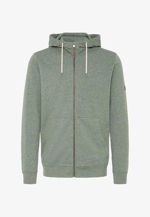 Grønn hettejakke med glidelås laget av myk materiale, med hette, snordekorer, frontlommer og ribbede mansjetter.