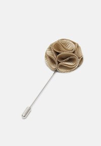 Broche de flor de tela beige con pétalos estratificados y acanalados; sujeta a un pin de metal plateado, que cuenta con un extremo redondeado para un cierre seguro.