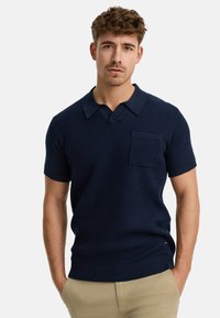Sötétkék, kötött polo ing ribbed textúrával, rövid ujjal és mellzsebekkel. Klasszikus gallérral és testhez simuló fazonnal rendelkezik.